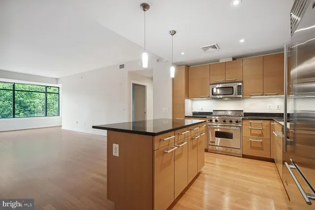 a kitchen with stainless steel appliances granite countertop a stove top oven a sink and a refrigerator