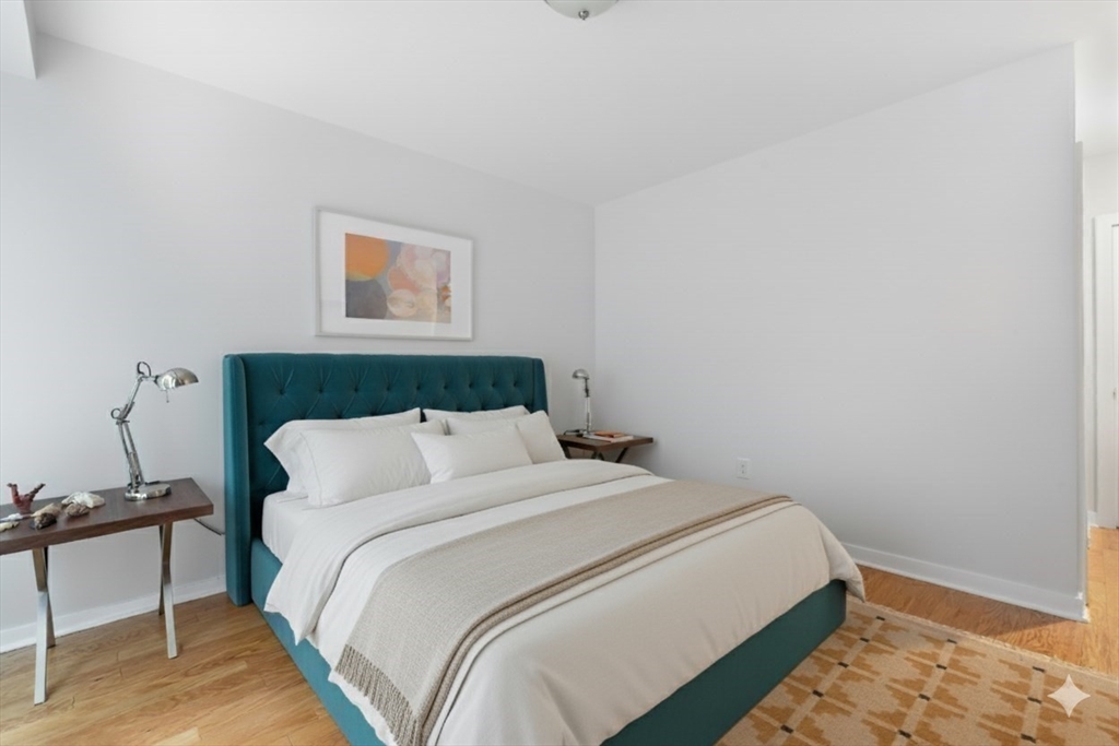 80 Broad Street, Unit 303 Boston, MA 02110 - Photo 12 of 23 a bedroom with a bed and a chair