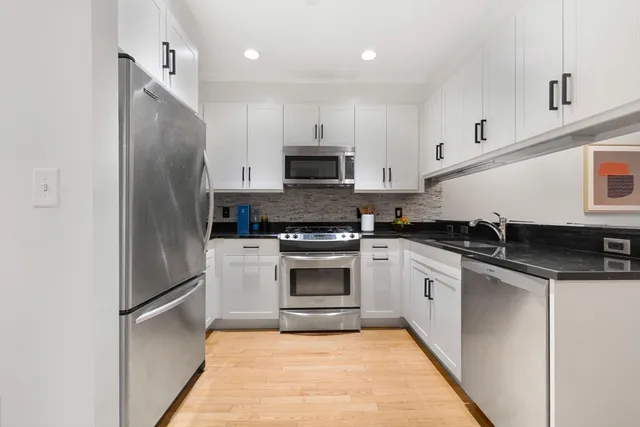 a kitchen with stainless steel appliances granite countertop a stove a refrigerator and a microwave