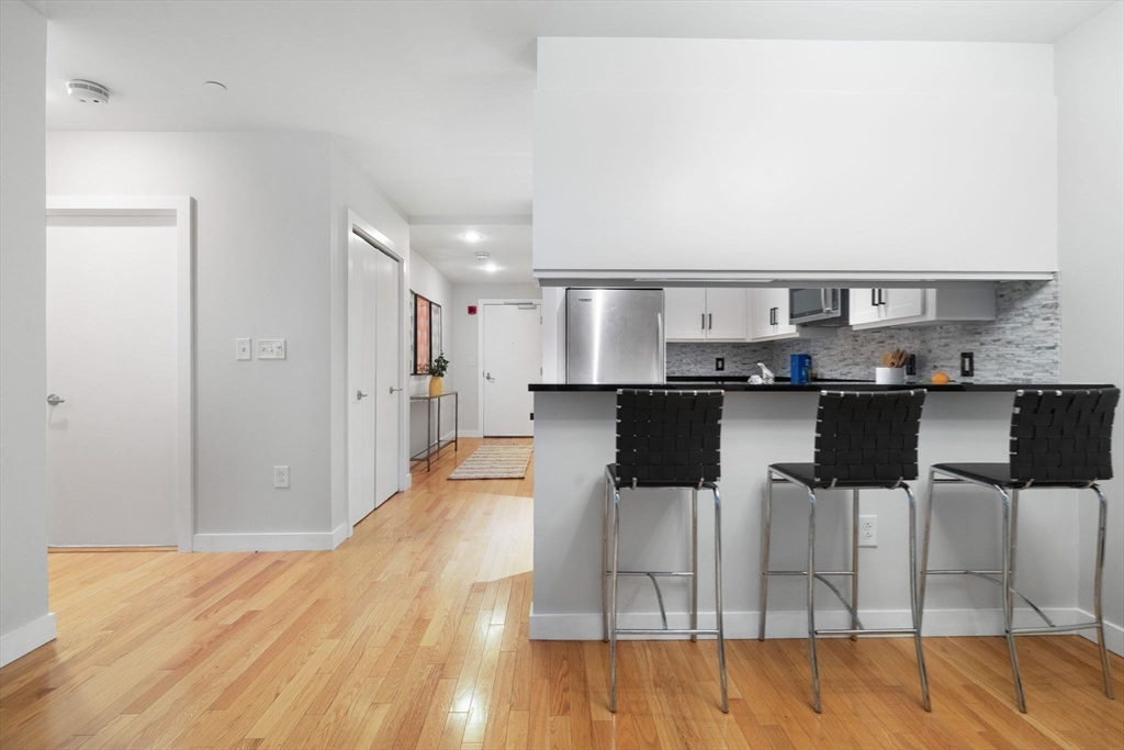 80 Broad Street, Unit 303 Boston, MA 02110 - Photo 9 of 23 a kitchen with stainless steel appliances kitchen island granite countertop a table and chairs in it