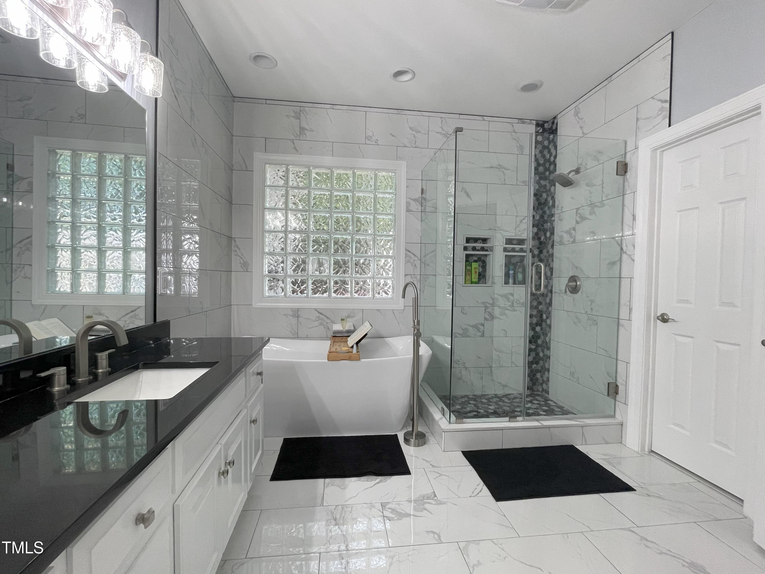 3033 Pearces Road Zebulon, NC 27597 - Photo 17 of 42 a spacious bathroom with a double vanity sink a large mirror and a shower