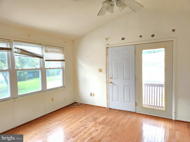 a view of an empty room with a window and wooden floor