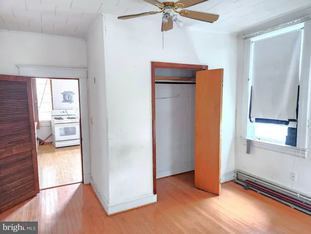 an empty room with wooden floor cabinet and windows