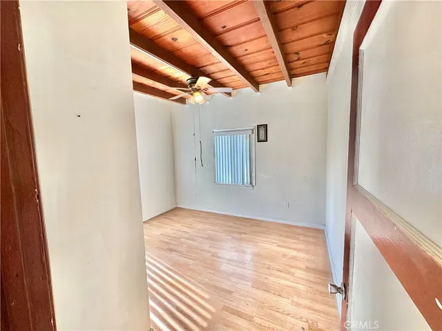 a view of empty room with wooden floor and fan