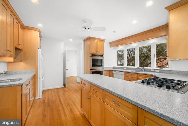 a large kitchen with stainless steel appliances a large counter top a stove and a refrigerator