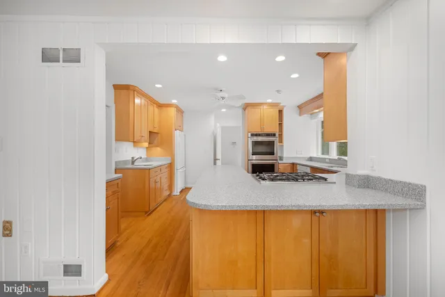 a view of a kitchen with kitchen island a counter top space a sink and a refrigerator