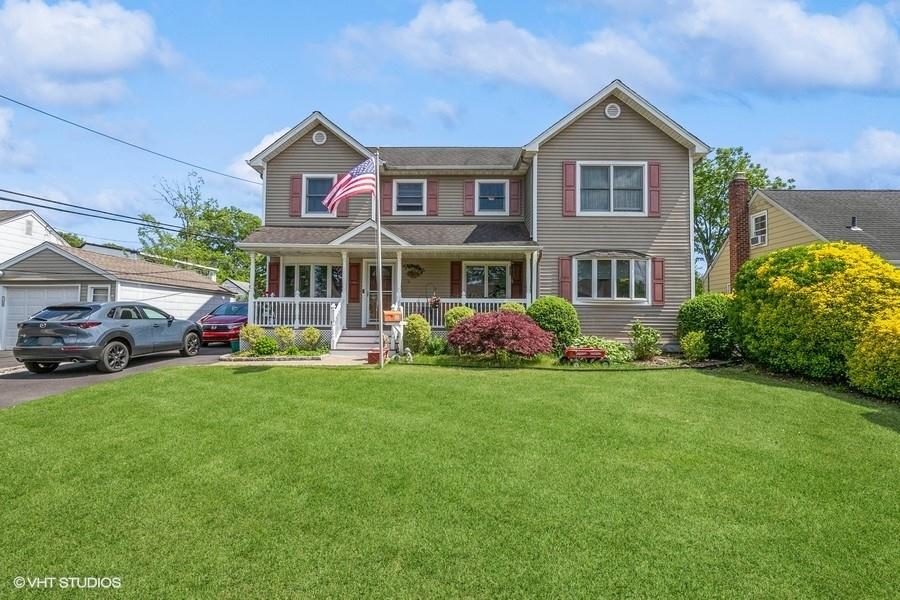 View of front of home featuring a porch, a front lawn, and a garage