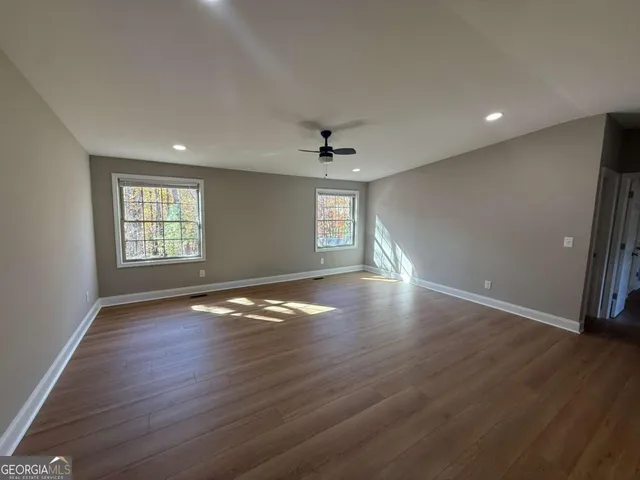 an empty room with wooden floor and windows