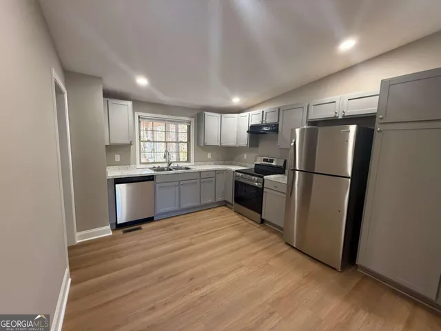 a kitchen with granite countertop stainless steel appliances a refrigerator a sink a window and cabinets