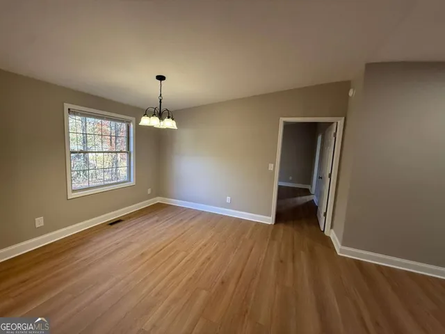 an empty room with wooden floor cabinet and windows