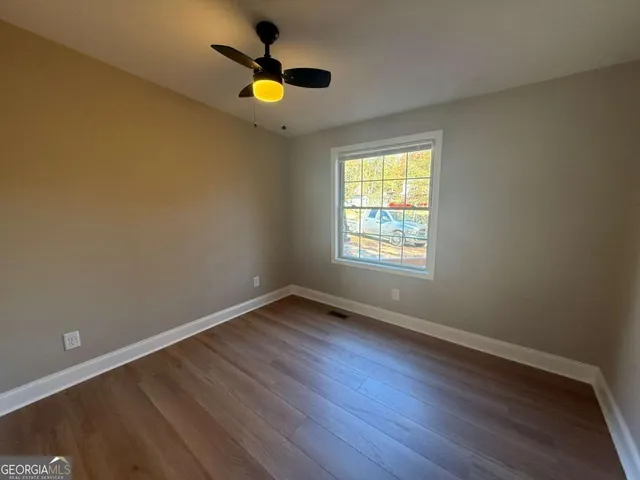 a view of an empty room with wooden floor and a window