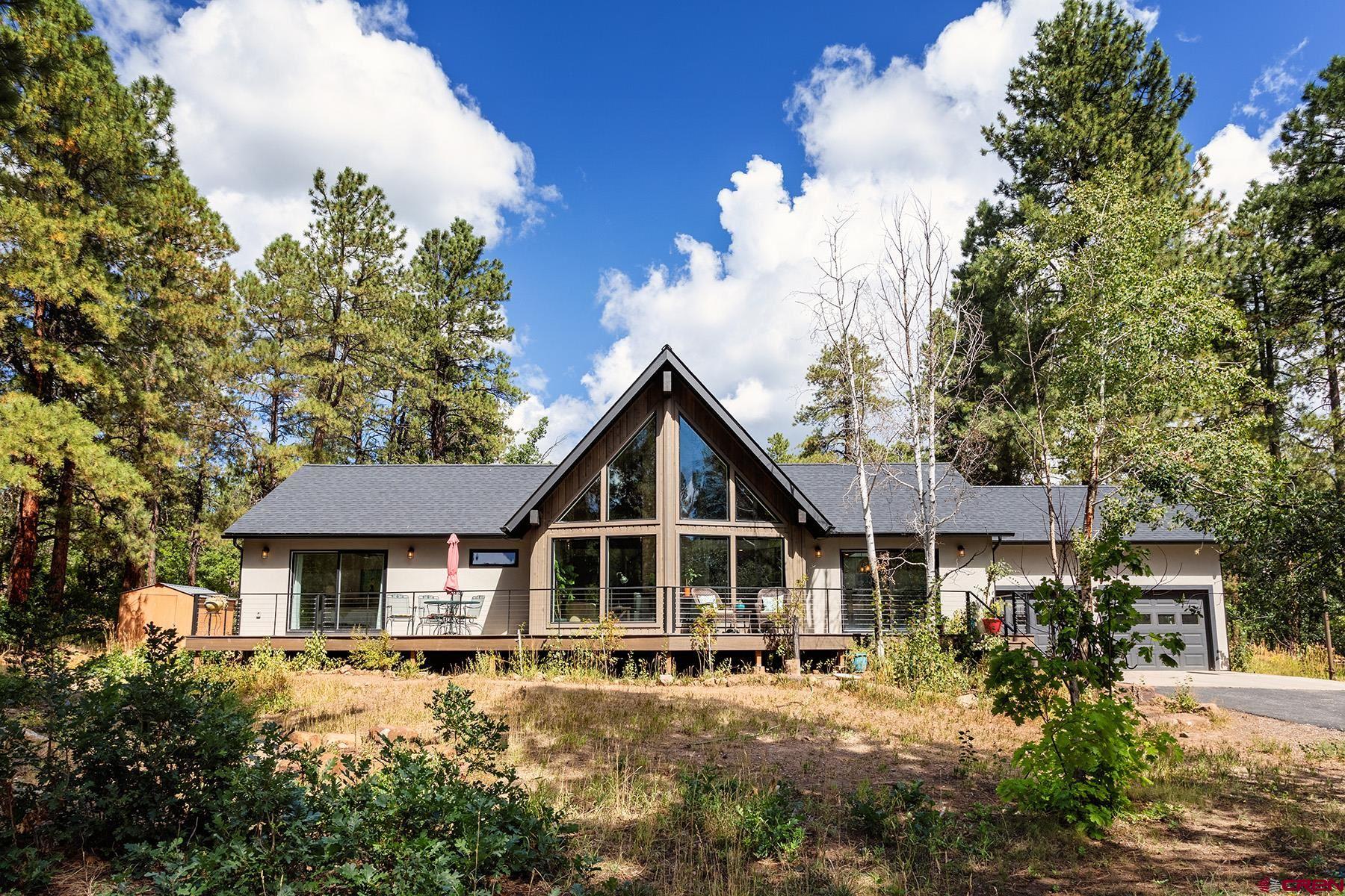a front view of a house with yard and trees around