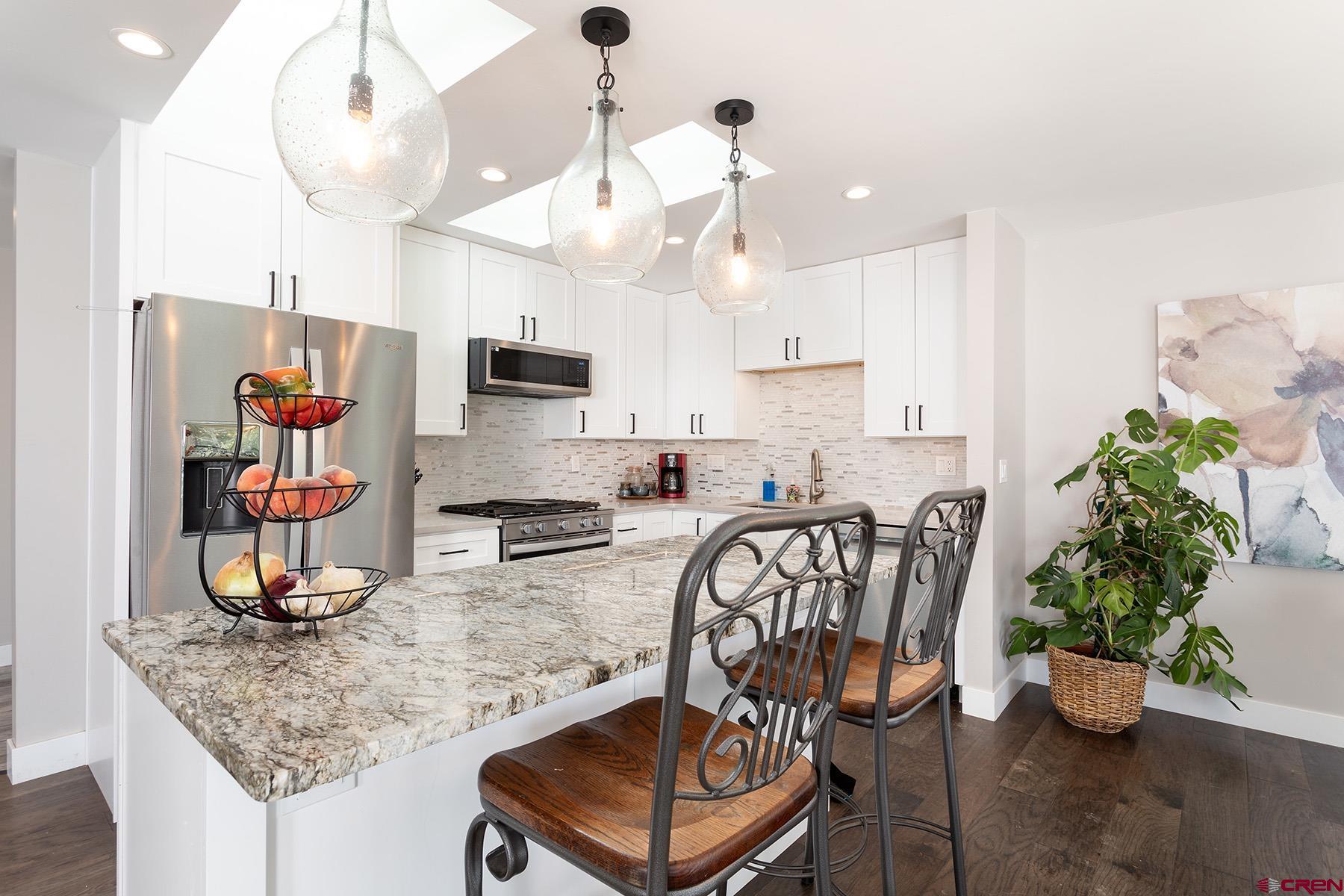 436 The Eagle Pass Durango, CO 81301 - Photo 10 of 29 a kitchen with stainless steel appliances kitchen island granite countertop a table chairs in it and wooden floor