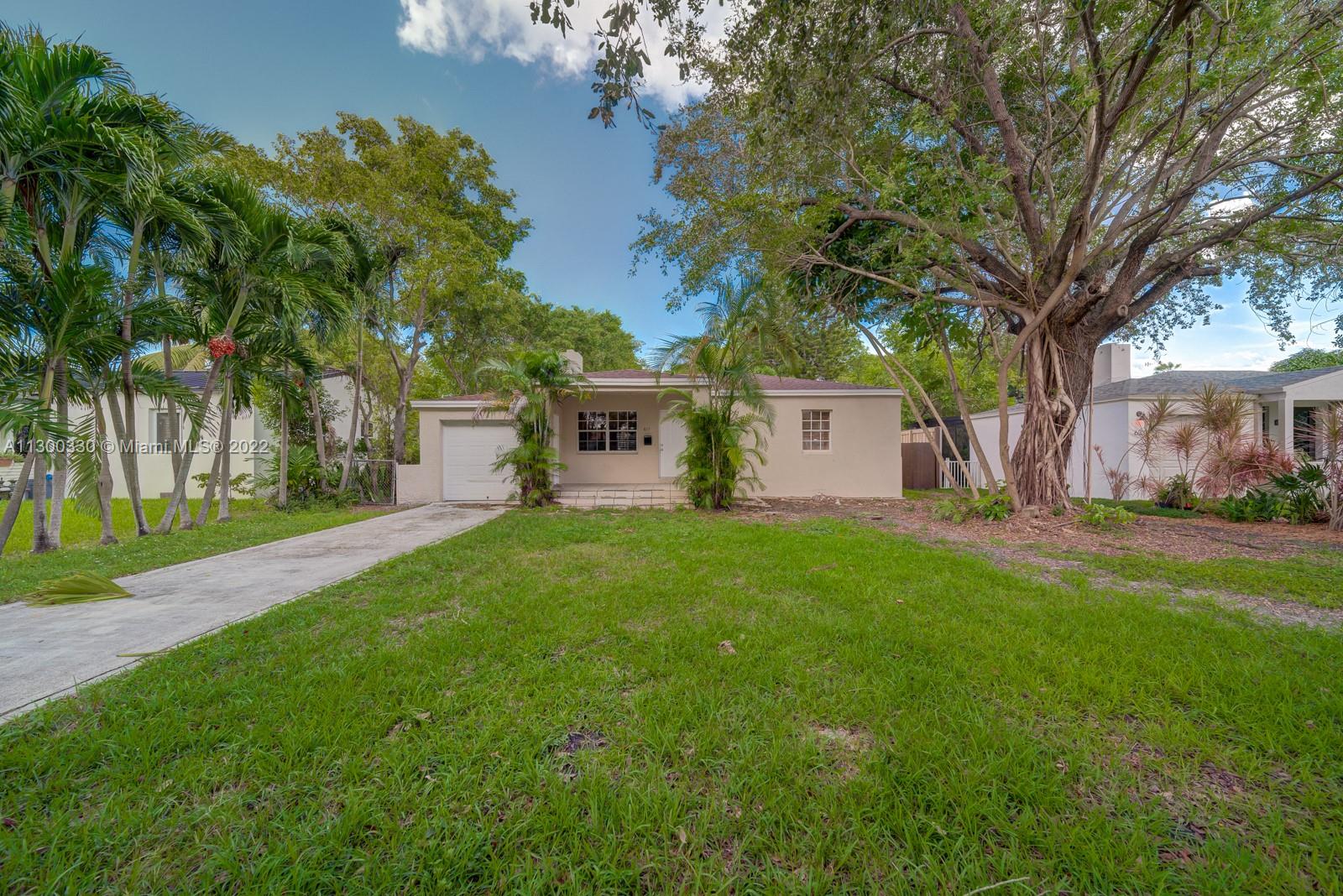 a view of a house with a yard and a large tree