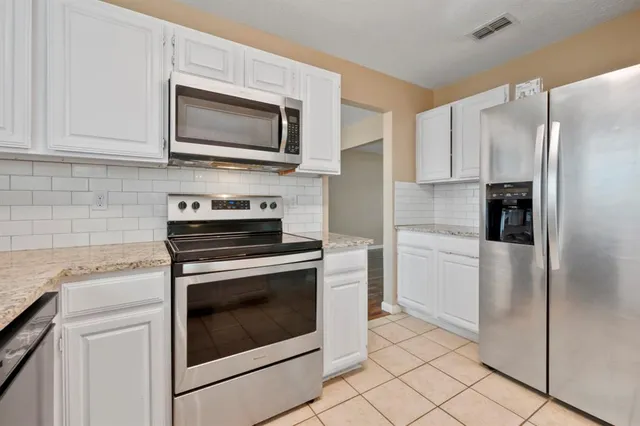 a kitchen with stainless steel appliances granite countertop a stove a refrigerator and a microwave