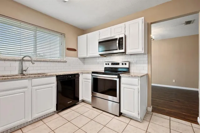 a kitchen with stainless steel appliances granite countertop white cabinets a sink and a oven