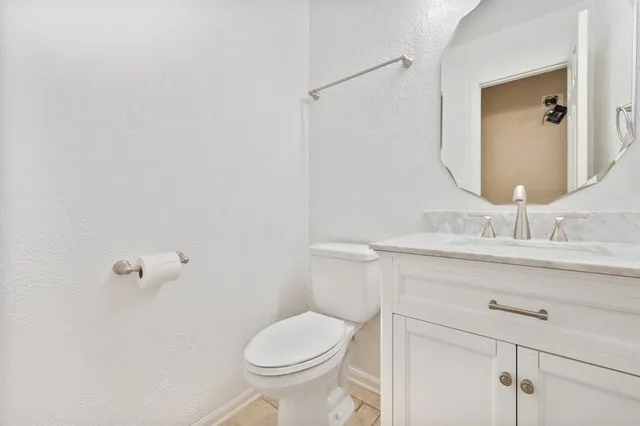 a bathroom with a granite countertop toilet sink and mirror
