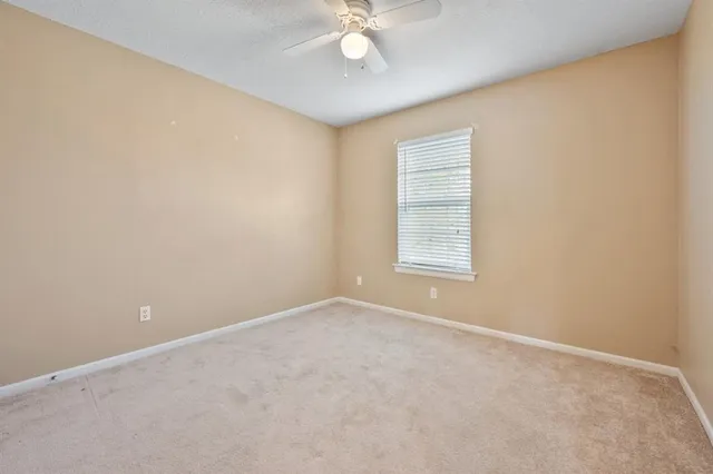 an empty room with a chandelier fan and windows