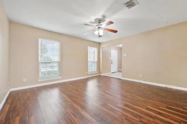 a view of an empty room with wooden floor and a window