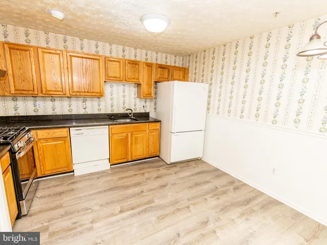 a kitchen with granite countertop a refrigerator a sink and cabinets