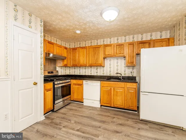 a kitchen with stainless steel appliances granite countertop a refrigerator a stove and a sink