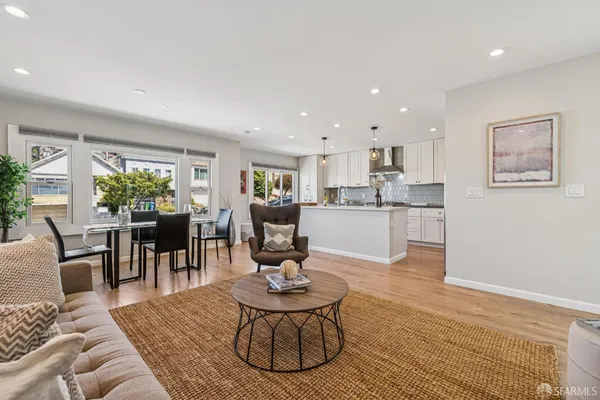 a living room with kitchen couches and kitchen view with wooden floor