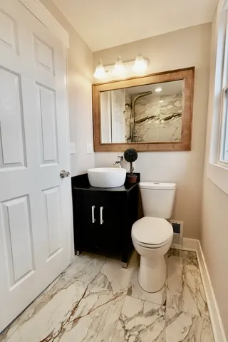 a bathroom with a granite countertop toilet a sink and a mirror