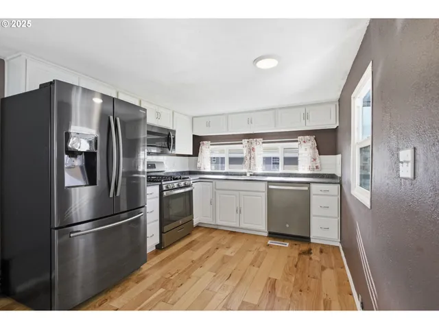 a kitchen with stainless steel appliances a refrigerator sink and white cabinets
