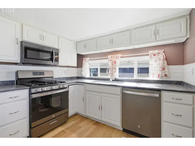 a kitchen with stainless steel appliances granite countertop a stove microwave and cabinets