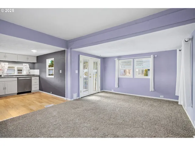 a view of an empty room with kitchen and a window