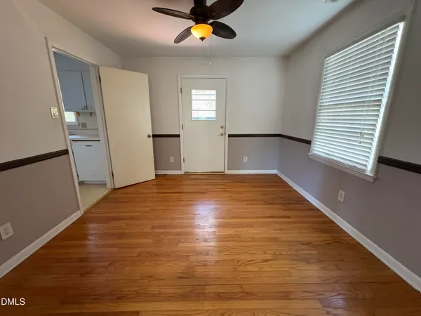 a view of empty room with wooden floor and fan