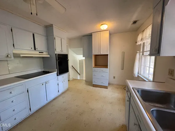 a kitchen with granite countertop a sink and white cabinets