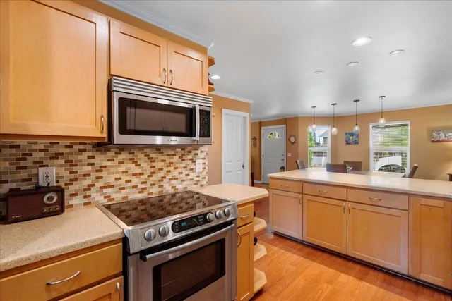 a kitchen with stainless steel appliances granite countertop a table chairs sink and cabinets