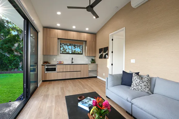 a living room with furniture kitchen view and a large window