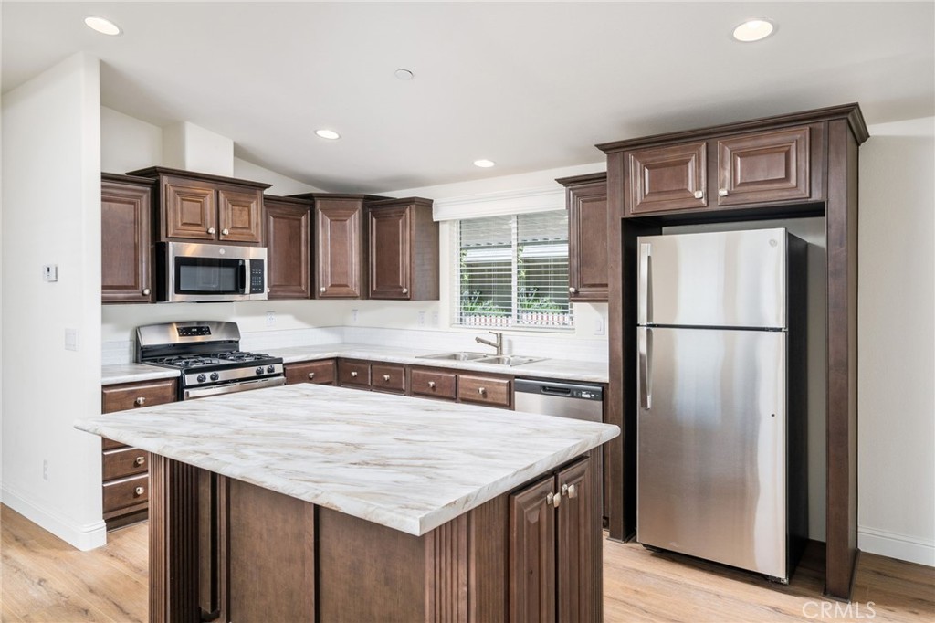 a kitchen with granite countertop a refrigerator a stove top oven a sink and dishwasher