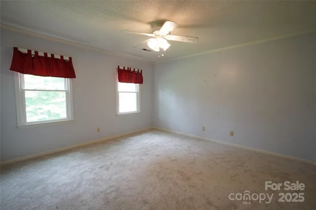 an empty room with windows and chandelier fan