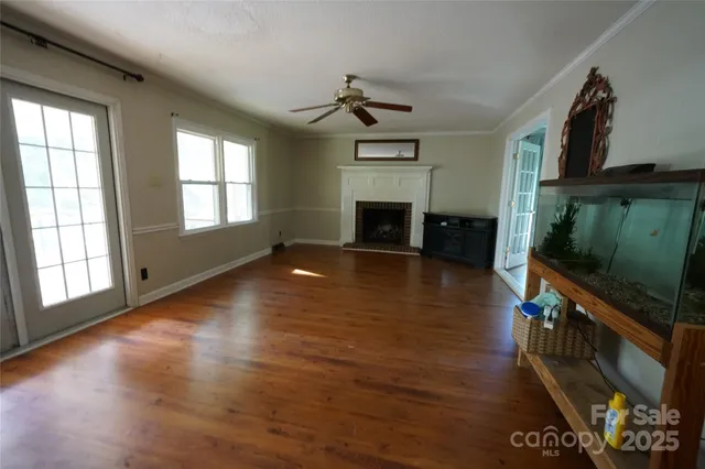 an empty room with windows fireplace and wooden floor