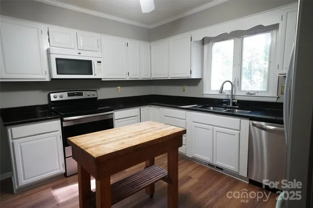 a kitchen with granite countertop a sink a stove and cabinets