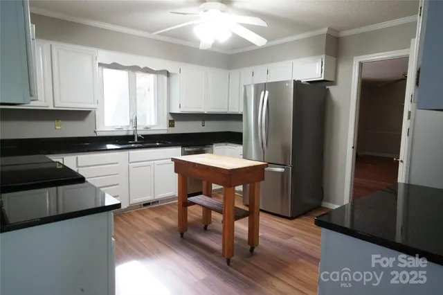 a kitchen with a refrigerator a sink a stove a dining table and chairs