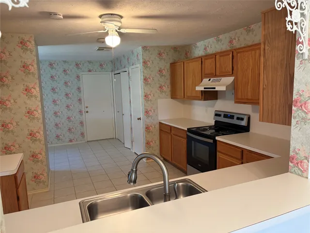 a kitchen with stainless steel appliances a stove a sink and a refrigerator with wooden floor