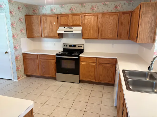 a kitchen with granite countertop a sink a stove top oven and cabinets