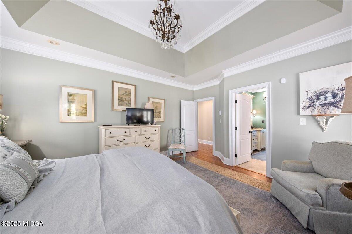 1060 East Magnolia Loop Madison, GA 30650 - Photo 20 of 41 a bedroom with a large bed and a chandelier