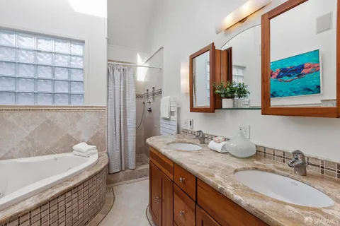a bathroom with a granite countertop tub sink and mirror