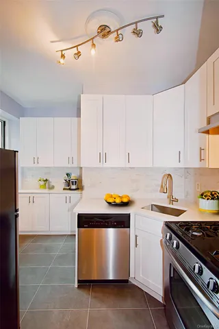 a kitchen with stainless steel appliances a stove a sink and white cabinets