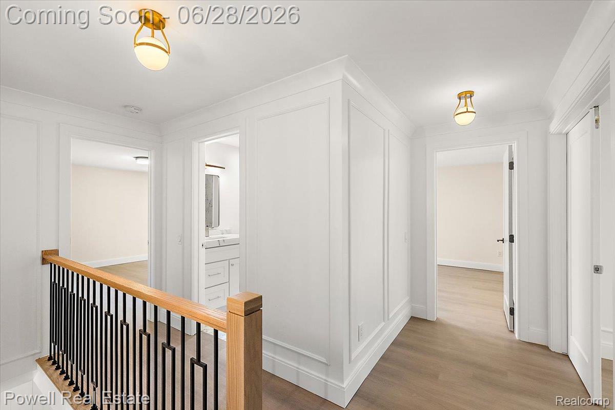 1447 Ravineview Court, Unit C12 Bloomfield Hills, MI 48304 - Photo 29 of 49 Upper-level hallway featuring wood-finish flooring, white paneled walls, and brass-tone ceiling light fixtures