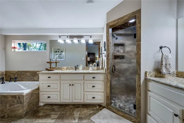 a bathroom with a granite countertop sink a large mirror and a bathtub