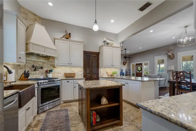 a kitchen with stainless steel appliances granite countertop a sink a stove and a refrigerator