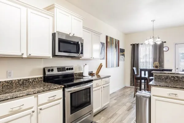 a kitchen with stainless steel appliances granite countertop a stove a sink and a microwave