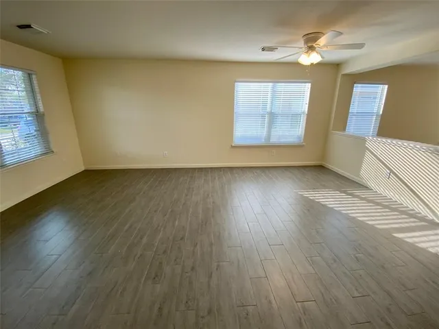 a view of an empty room with wooden floor and a window