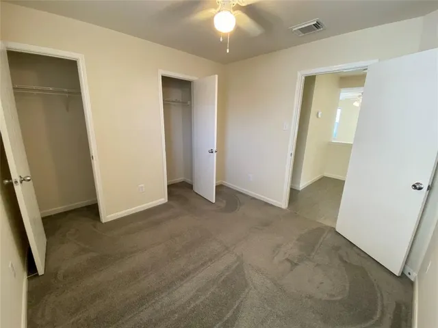 an empty room with closet and a chandelier fan